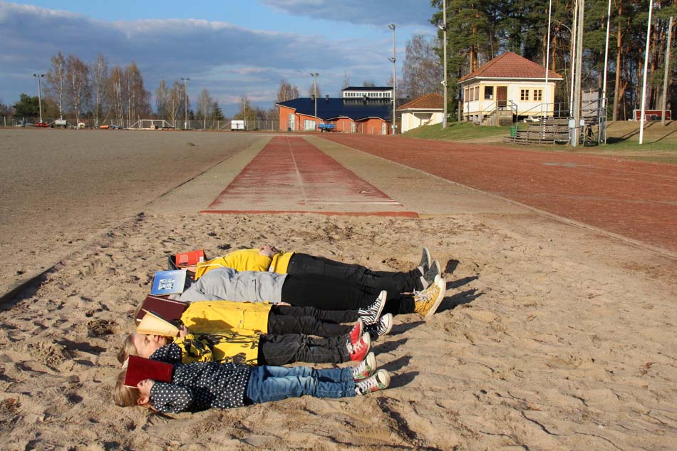 a group of kids laying in a sandbox and reading books