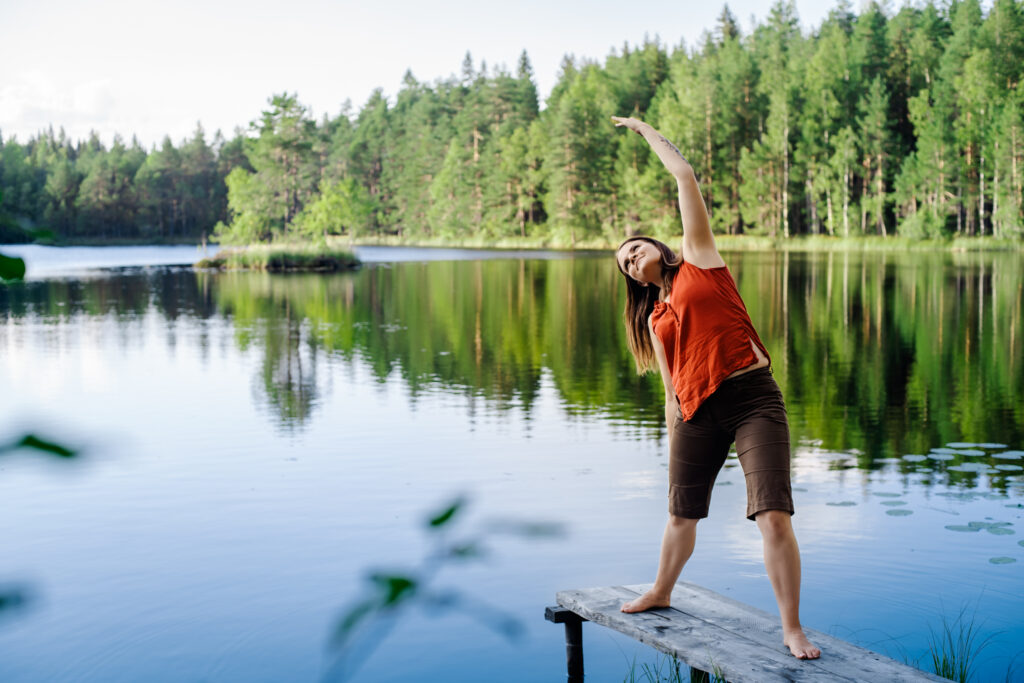 aikuinen venyttelee laiturilla kesämaisemassa